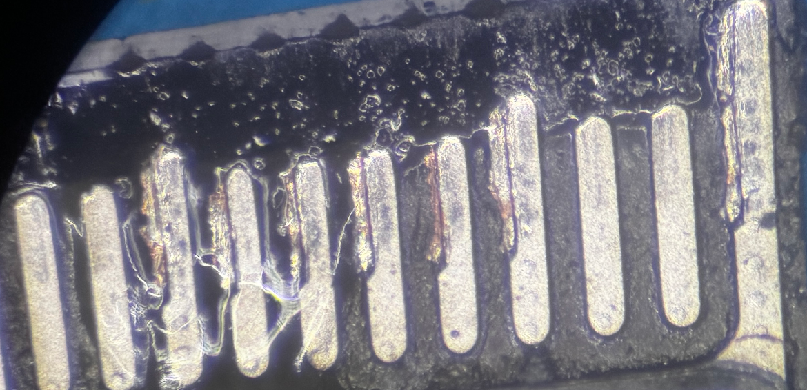 Microscope eyepiece view of a crushed MacBook USB-C charging connector